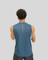 Person wearing a blue sleeveless shirt with branding on the back against a gray background