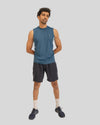 Man wearing a blue sleeveless shirt and black shorts on a light gray background