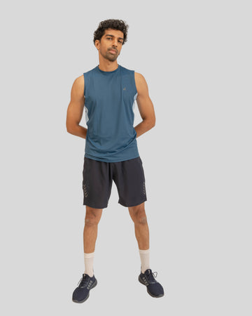 Man wearing a blue sleeveless shirt and black shorts on a light gray background