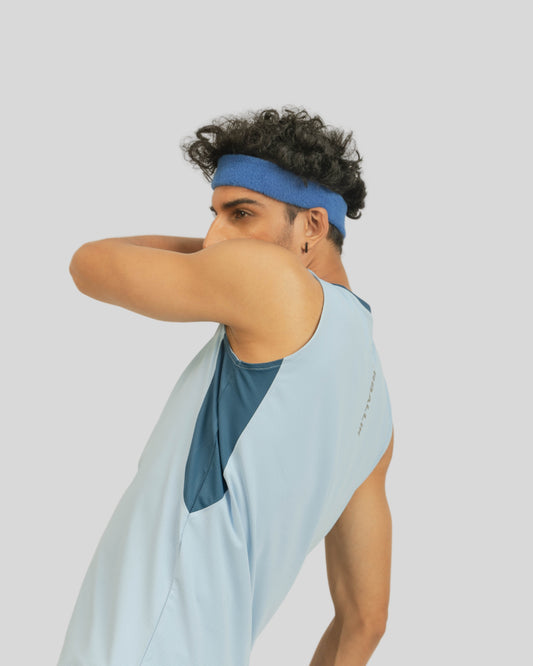 Person wearing a light blue sleeveless top with a geometric design on a plain background