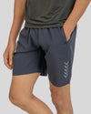 Person wearing dark gray athletic shorts with a subtle pattern on a light gray background