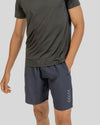 Person wearing a dark gray t-shirt and shorts on a light gray background