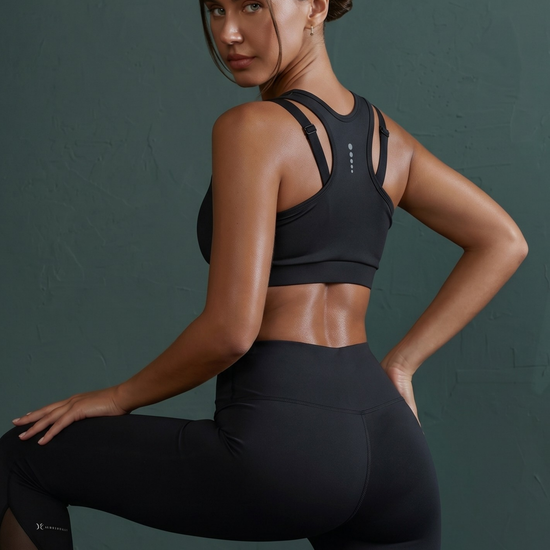Woman wearing a black sports bra and leggings against a dark background