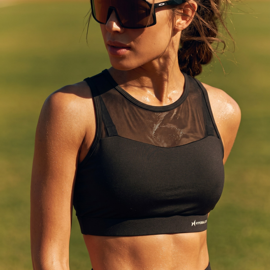 Woman wearing a black sports bra and sunglasses outdoors
