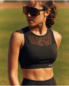 Woman wearing a black sports bra and sunglasses outdoors