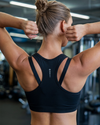 Woman in a black sports bra performing an exercise in a gym setting