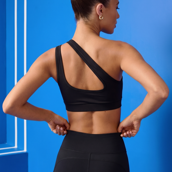 Woman wearing a black sports bra and leggings against a blue background