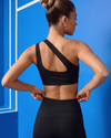 Woman wearing a black sports bra and leggings against a blue background