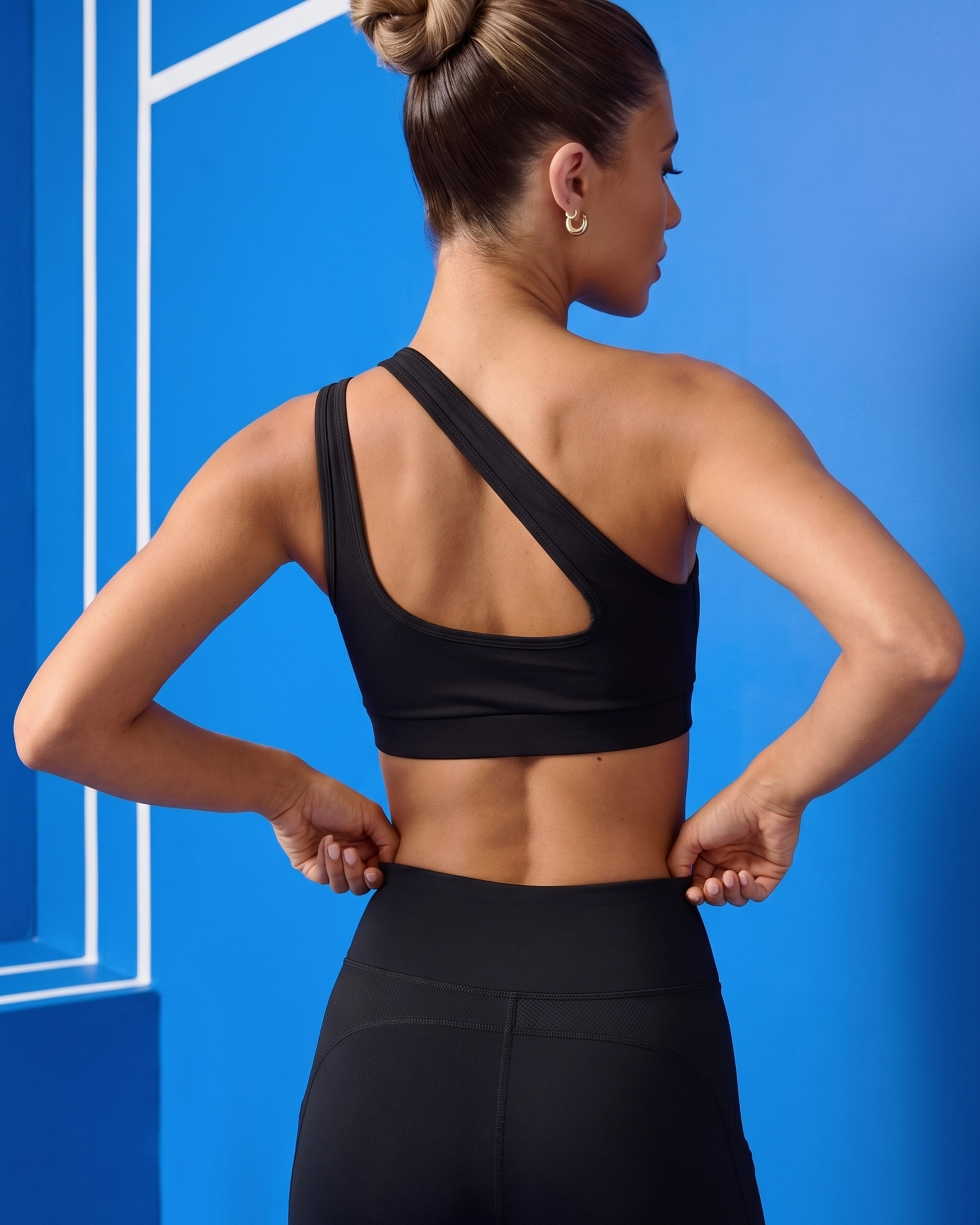Woman wearing a black sports bra and leggings against a blue background