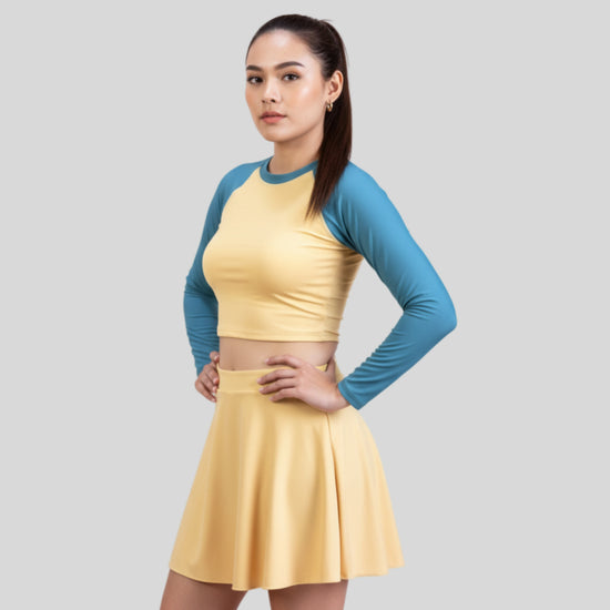 Woman wearing a yellow dress with blue sleeves on a gray background