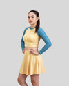 Woman wearing a yellow dress with blue sleeves on a gray background