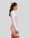 Woman wearing a pink and white long-sleeve outfit on a plain background