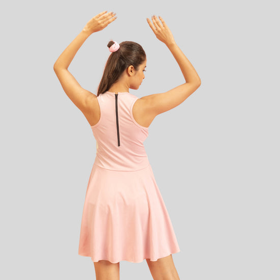 Woman wearing a pink dress with her arms raised on a gray background