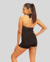 Woman wearing a black halter neck swimsuit against a gray background