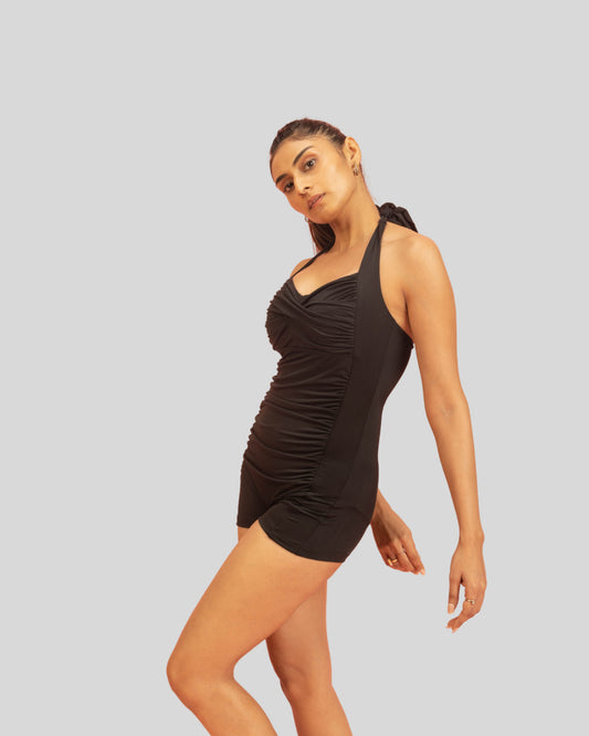 Woman wearing a black one-shoulder swimsuit on a light gray background