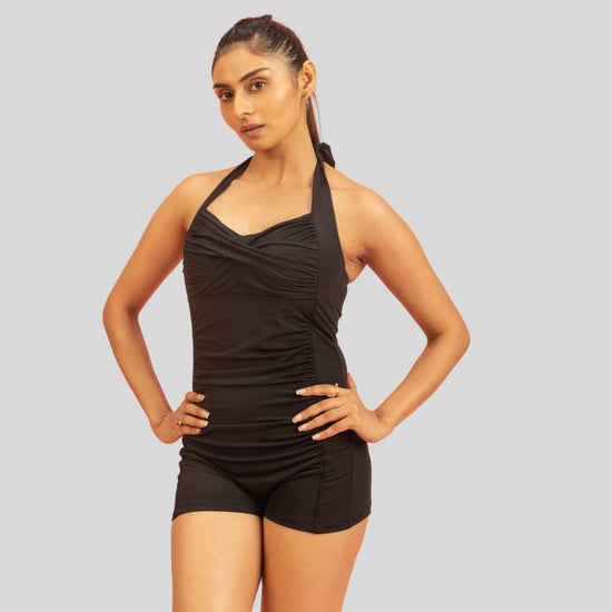 Woman wearing a black swimsuit against a gray background
