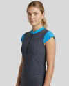Woman wearing a gray sleeveless top with blue accents on a light gray background