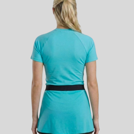 Person wearing a turquoise dress with a black belt on a light gray background