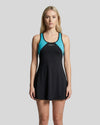 Woman wearing a black and teal dress with a visible brand logo on a gray background