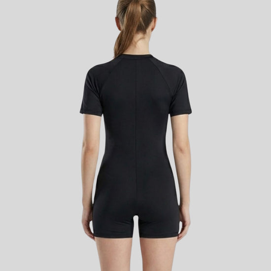 Person wearing a black bodysuit against a light gray background