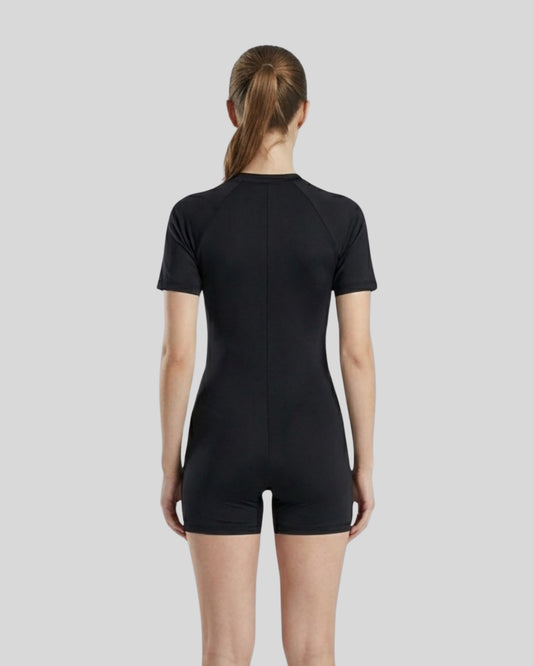 Person wearing a black bodysuit against a light gray background