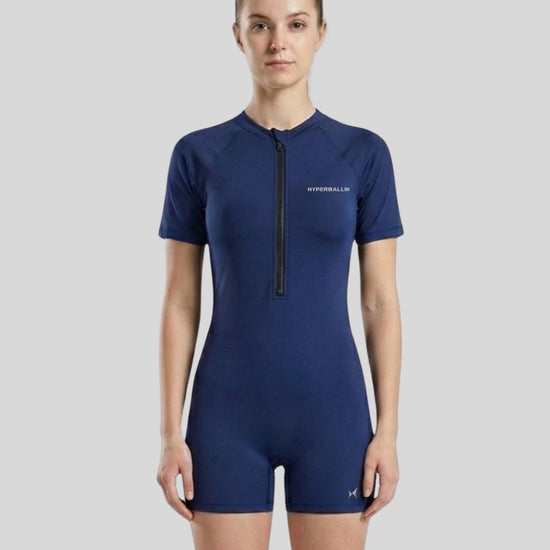 Woman wearing a blue swimsuit with a zipper on a gray background