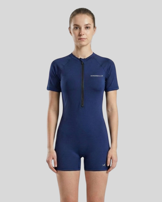Woman wearing a blue swimsuit with a zipper on a gray background