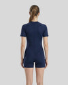 Person wearing a navy blue bodysuit on a light gray background