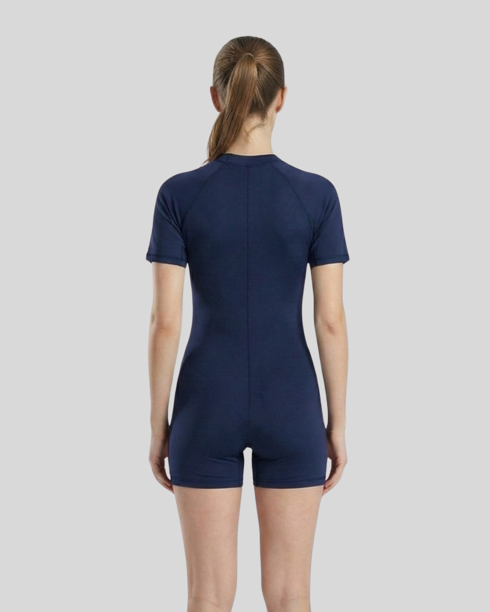 Person wearing a navy blue bodysuit on a light gray background