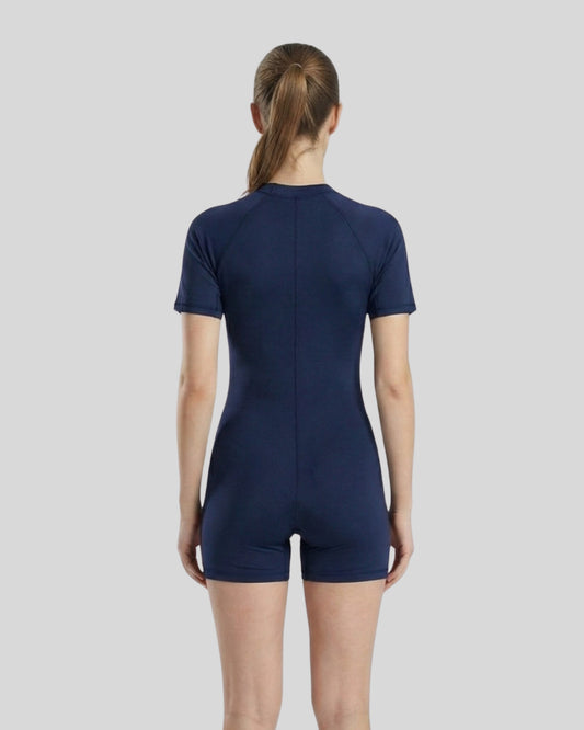 Person wearing a navy blue bodysuit on a light gray background