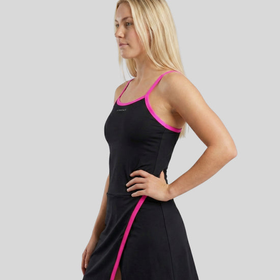 Woman wearing a black dress with pink trim on a gray background