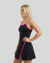 Woman wearing a black dress with pink trim on a gray background