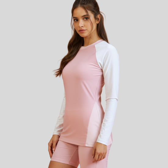 Woman wearing a pink and white long-sleeve top with matching shorts on a light gray background