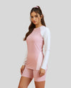 Woman wearing a pink and white long-sleeve top with matching shorts on a light gray background