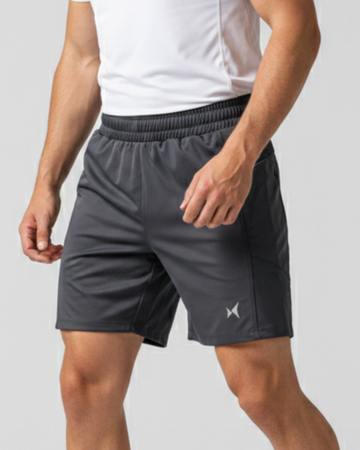 Person wearing gray athletic shorts with a brand logo on a light gray background