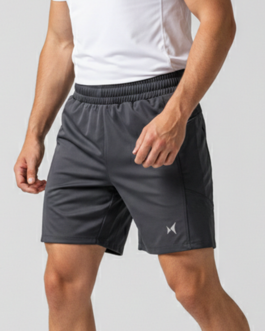 Person wearing gray athletic shorts with a brand logo on a light gray background