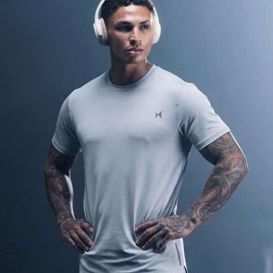 Man wearing a light gray t-shirt and headphones against a dark background