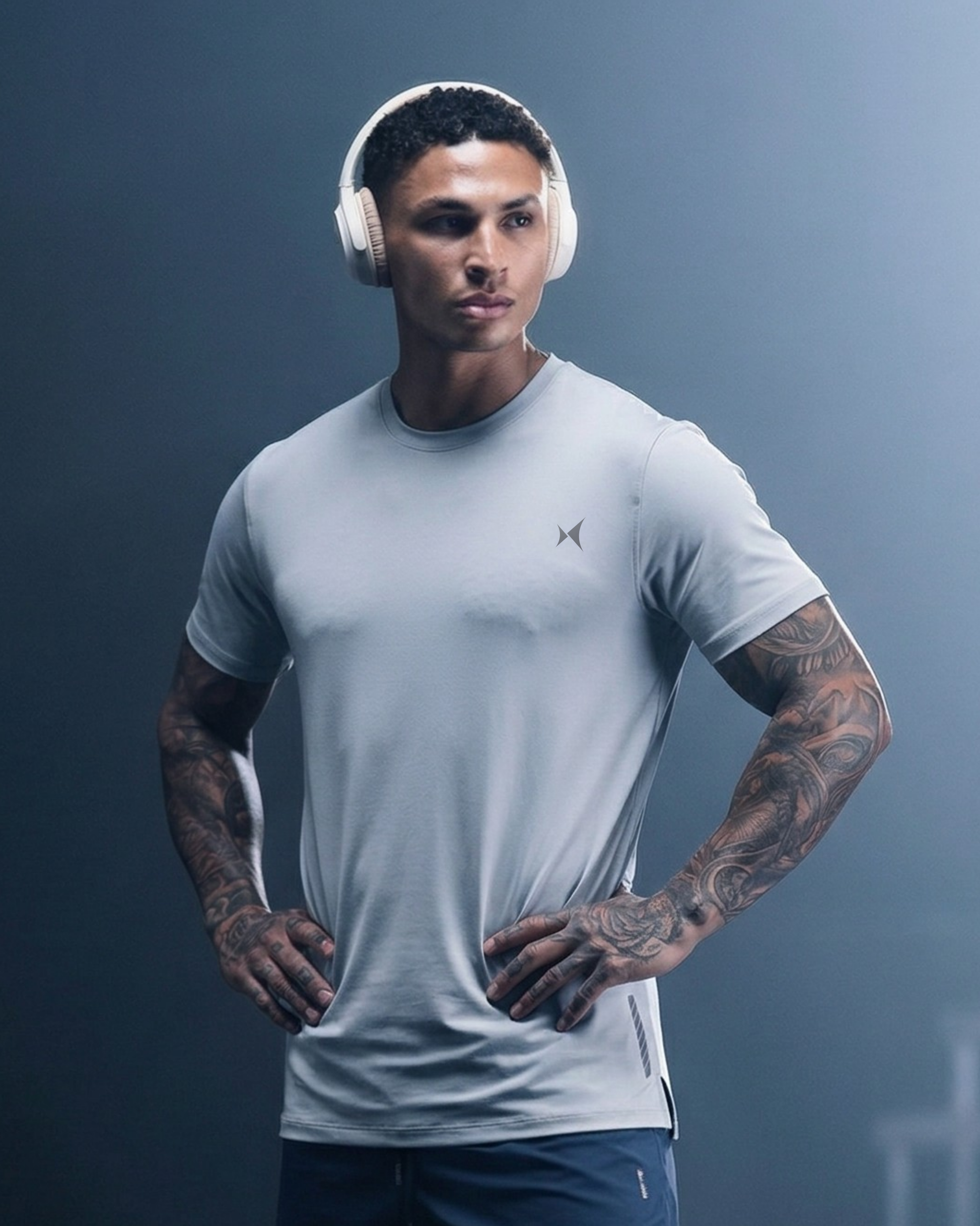 Man wearing a light gray t-shirt and headphones against a dark background