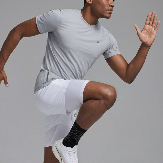 Man in athletic wear performing a squat against a gray background