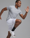 Man in athletic wear performing a squat against a gray background