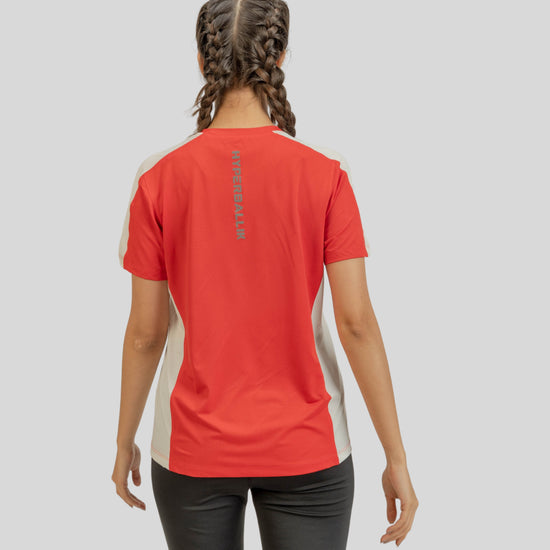 Person wearing a red athletic shirt with a logo on the back against a gray background