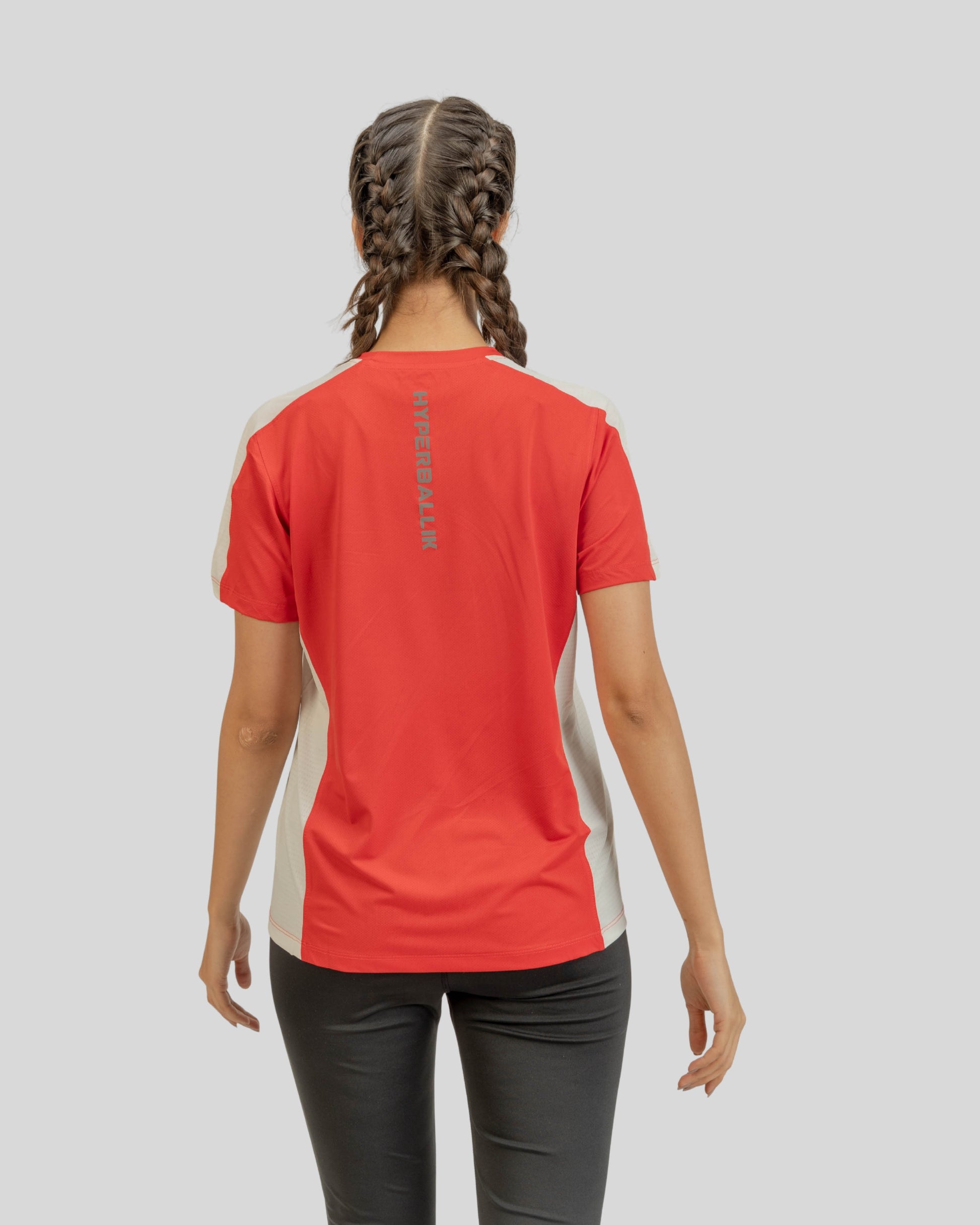 Person wearing a red athletic shirt with a logo on the back against a gray background