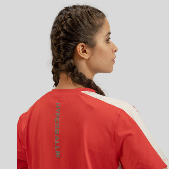 Person wearing a red and white sports jersey with a logo on the back against a light gray background