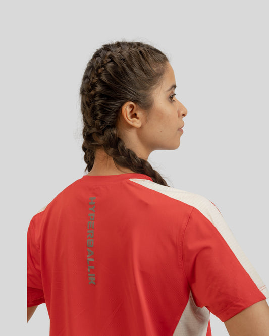 Person wearing a red and white sports jersey with a logo on the back against a light gray background