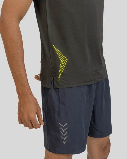 Person wearing a black athletic shirt with a yellow logo and dark shorts on a gray background
