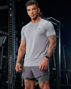 Man wearing a gray athletic outfit with visible tattoos in a gym setting
