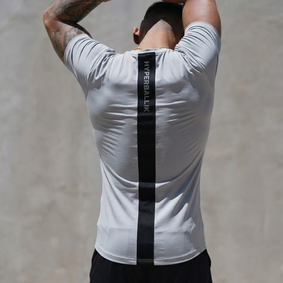 Person wearing a white athletic shirt with a black stripe on a plain background