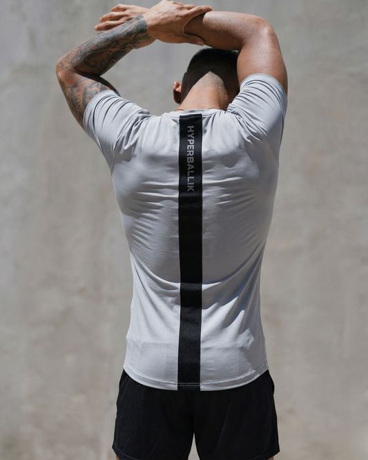 Person wearing a white athletic shirt with a black stripe on a plain background