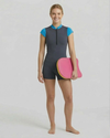 Person wearing a gray and blue swimsuit holding a pink浮板 on a white background