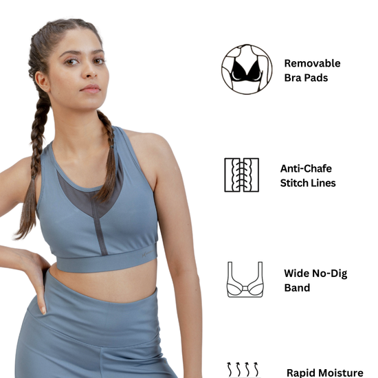 Woman wearing a blue athletic outfit with text indicating features like removable bra pads, anti-chafe stitch lines, wide no-dig band, and rapid moisture wicking.